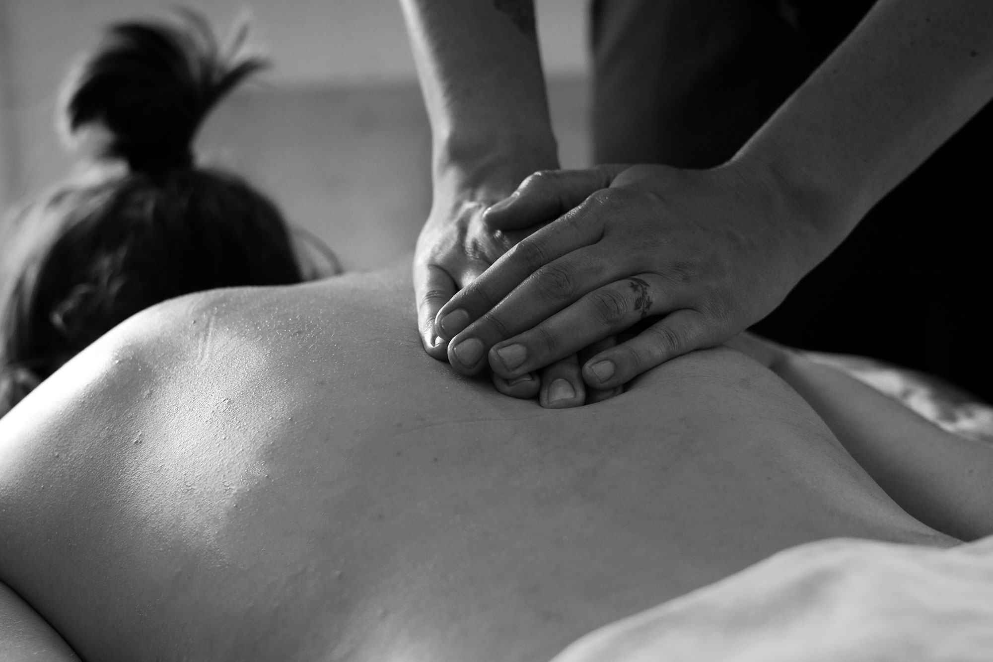 A massage therapist uses their hands to provide therapy to an exposed back.